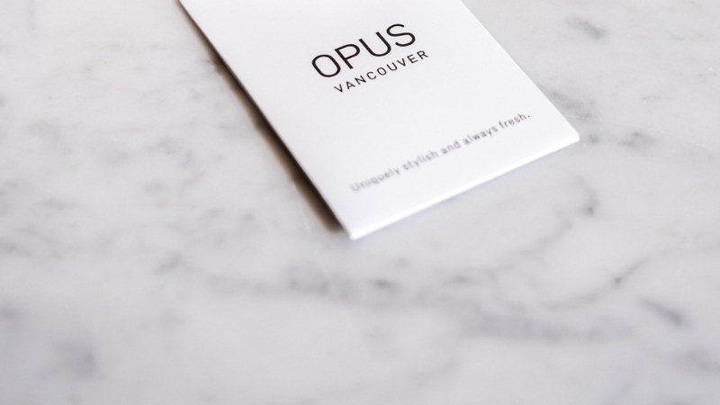 OPUS Vancouver branded welcome card resting on a white marble surface